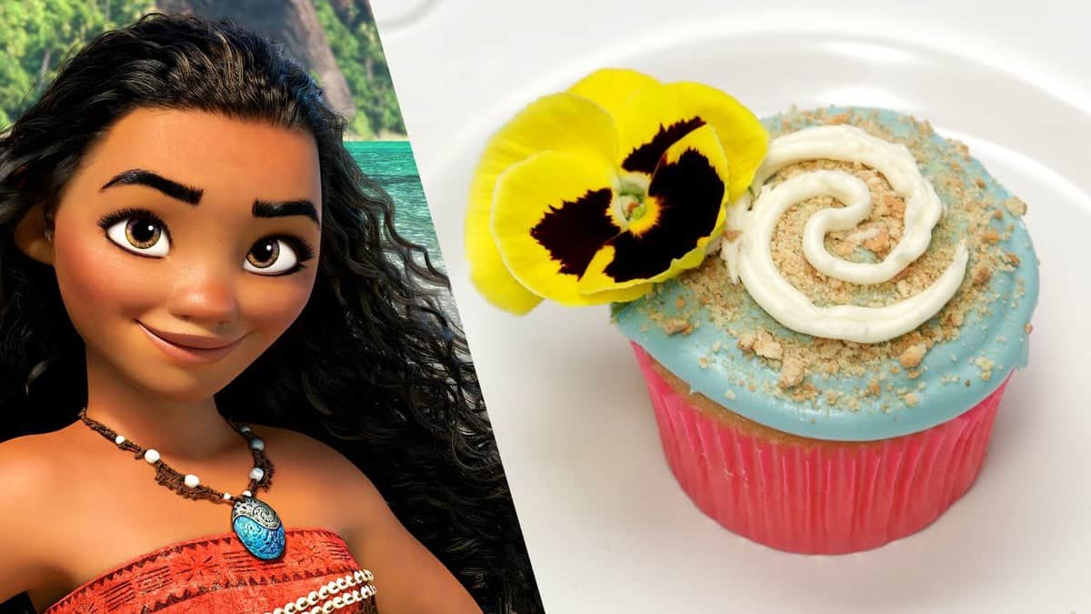 Moana in a tropical setting next to themed cupcakes with ocean-blue swirled icing and a yellow flower, perfect for Disney fans.