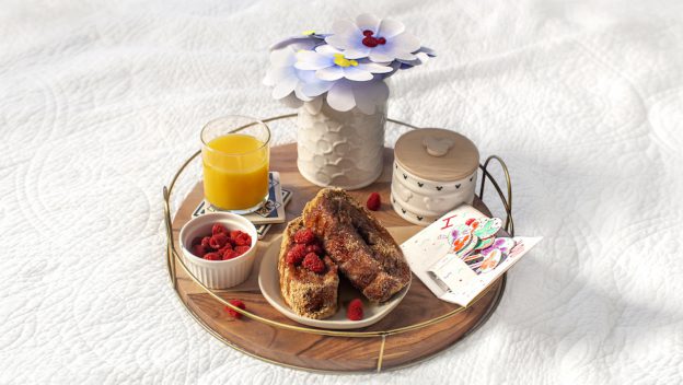Magical Disney-themed breakfast tray with French toast, raspberries, OJ, card, and paper flowers—Mother’s Day park delight!.