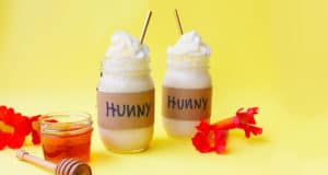 Sip on the magic: glass Hunny jars of creamy shakes, honey, and blooms pop against yellow—Winnie the Pooh treat at Disney Parks.