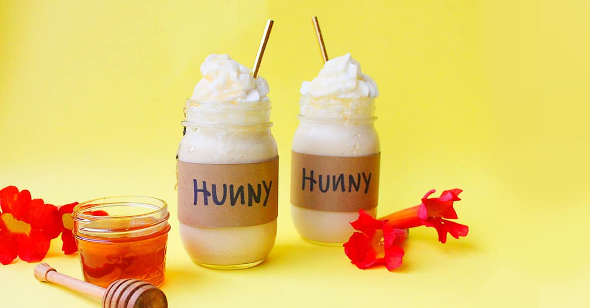 Sip on the magic: glass Hunny jars of creamy shakes, honey, and blooms pop against yellow—Winnie the Pooh treat at Disney Parks.