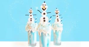 Olaf-themed Frozen milkshakes, blue and white, topped with marshmallow snowmen and candy, perfect for Disney Parks fans.