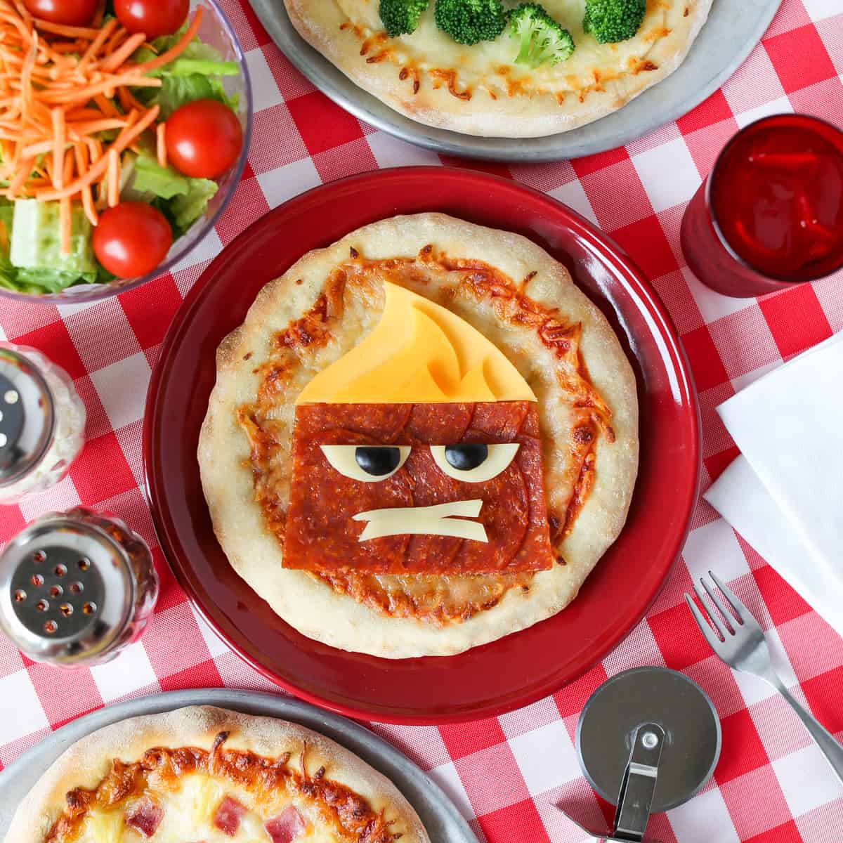 Anger Pizza with extra cheese and pepperoni forms a cartoon scowl on a red plate—an animated snack worthy of Toon Town!.