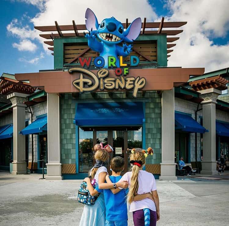Disney fans in costume strike a pose outside the World of Disney at Disney Springs, under the giant Stitch perched above the entrance.