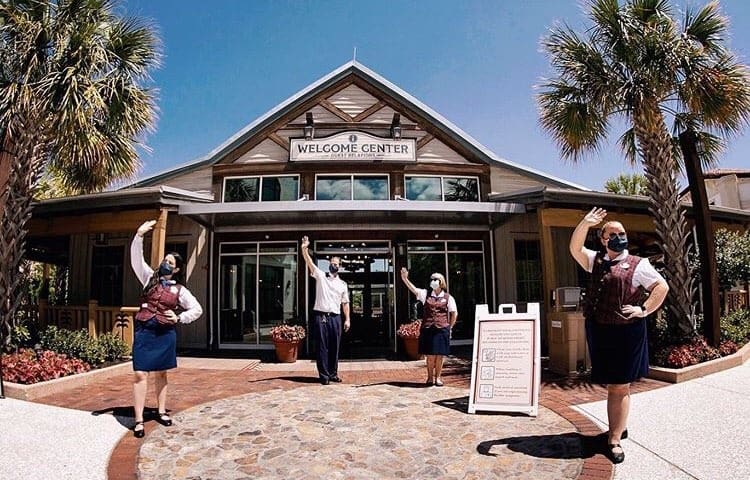 Disney Springs cast members in masks wave outside the Welcome Center, ready to greet guests and capture magical moments.
