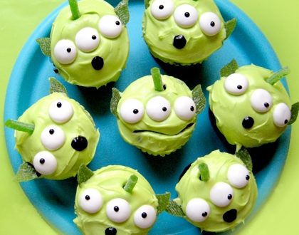 Toy Story alien cupcakes with googly eyes and candy ears, arranged on a blue plate like a Pixar Pier treat.
