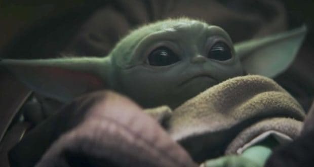 Grogu cozily wrapped in his brown blanket, gazing up with wonder—capturing the magic of Star Wars at Galaxy’s Edge.