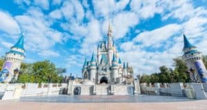 Cinderella Castle with blue spires glows beneath a bright sky, as Disney fans reserve their visit with the Park Pass System.