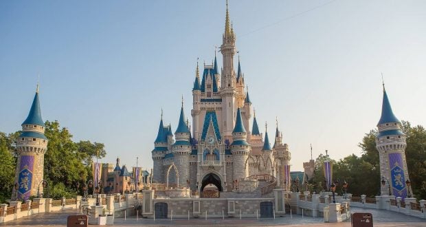 Cinderella Castle’s iconic blue spires rise above Main Street, enchanting Disney World guests under a sunny, cloudless sky.