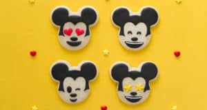 Four Mickey Mouse emoji cookies on a yellow background with hearts and stars—Disney magic for fans and party inspo!.