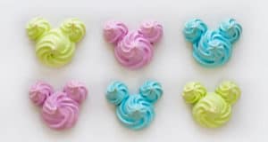 Colorful Mickey Mouse-shaped pastel meringues in yellow, pink, and blue, ready for Disney fans to recreate at home.