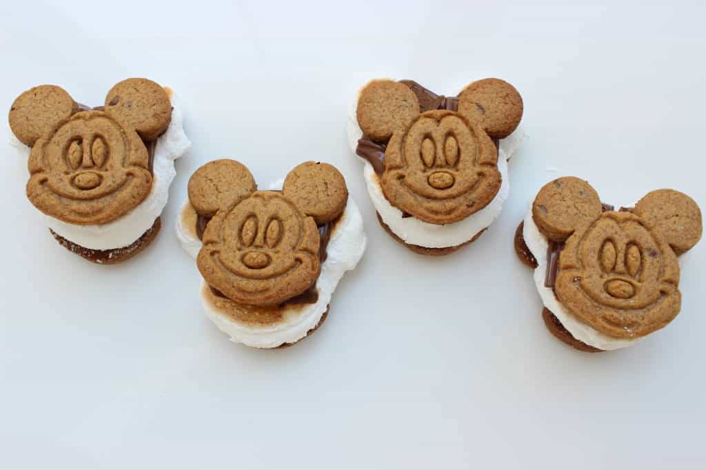Four Mickey-shaped s'mores with marshmallow and chocolate—perfect Disney park treats for fans, set on a white background.