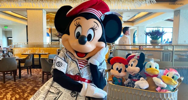 Minnie Mouse greets guests in a Disney World restaurant beside a basket of plush characters, adding magic to the dining experience.