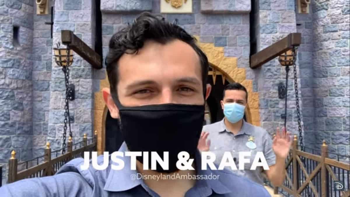 Justin and Rafa, both wearing masks, pose in front of the Disneyland castle with a sign saying "JUSTIN & RAFA – Welcome Back Guests.