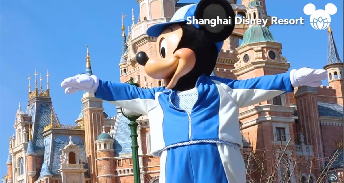 Mickey Mouse, dressed in blue and white, joyfully stretches his arms wide for International Yoga Day at Shanghai Disney Resort.
