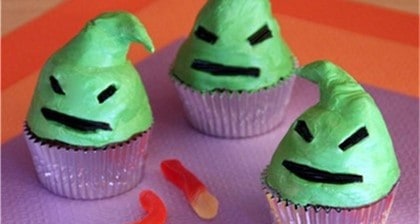 Oogie Boogie cupcakes with green spooky faces and candy worms sit on a purple napkin, perfect for a Disney Halloween treat.