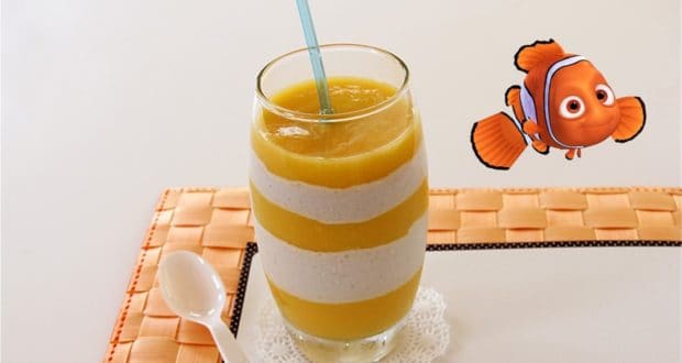 A playful Nemo smoothie, layered with mango and cream, topped with a blue straw and cartoon clownfish—pure Disney magic!.