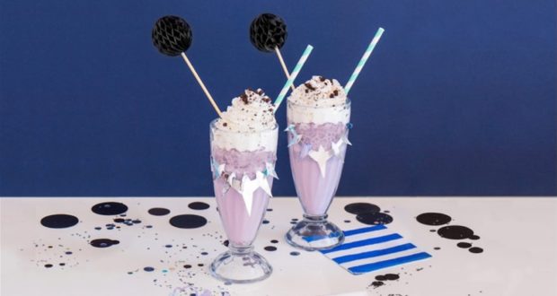 Enjoy two Black Panther-inspired purple milkshakes with whipped cream and sprinkles, perfect for your next Marvel park adventure!.