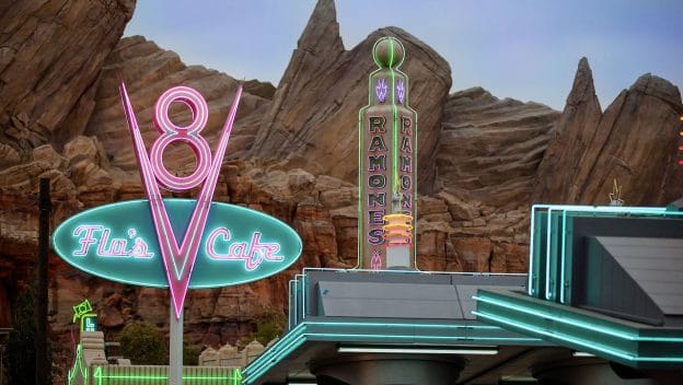 Flo's V* Cafe neon sign in pink and blue and Ramone's before a rock formation