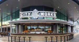 City Works Eatery at Disney Springs, sporting its bold sign, lively outdoor bar, and sleek glass facade after reopening.