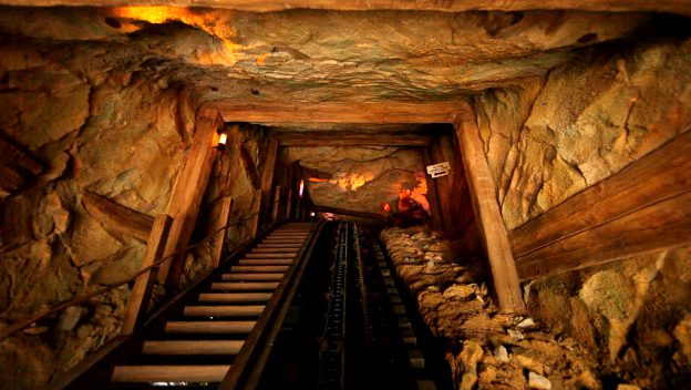 Big Grizzly Mountain Runaway Mine Cars climbs into a shadowy, wooden and rocky mine tunnel at Hong Kong Disneyland.