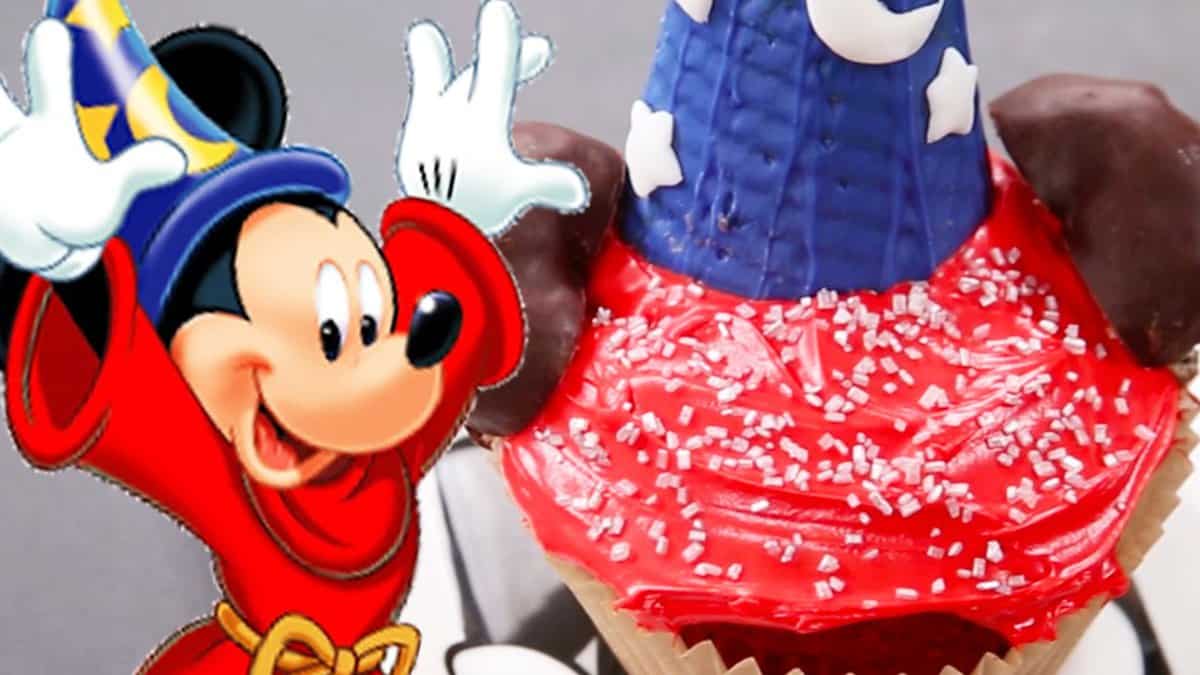 Mickey as the Sorcerer's Apprentice poses by a colorful cupcake, bringing Disney magic to your day at the park.