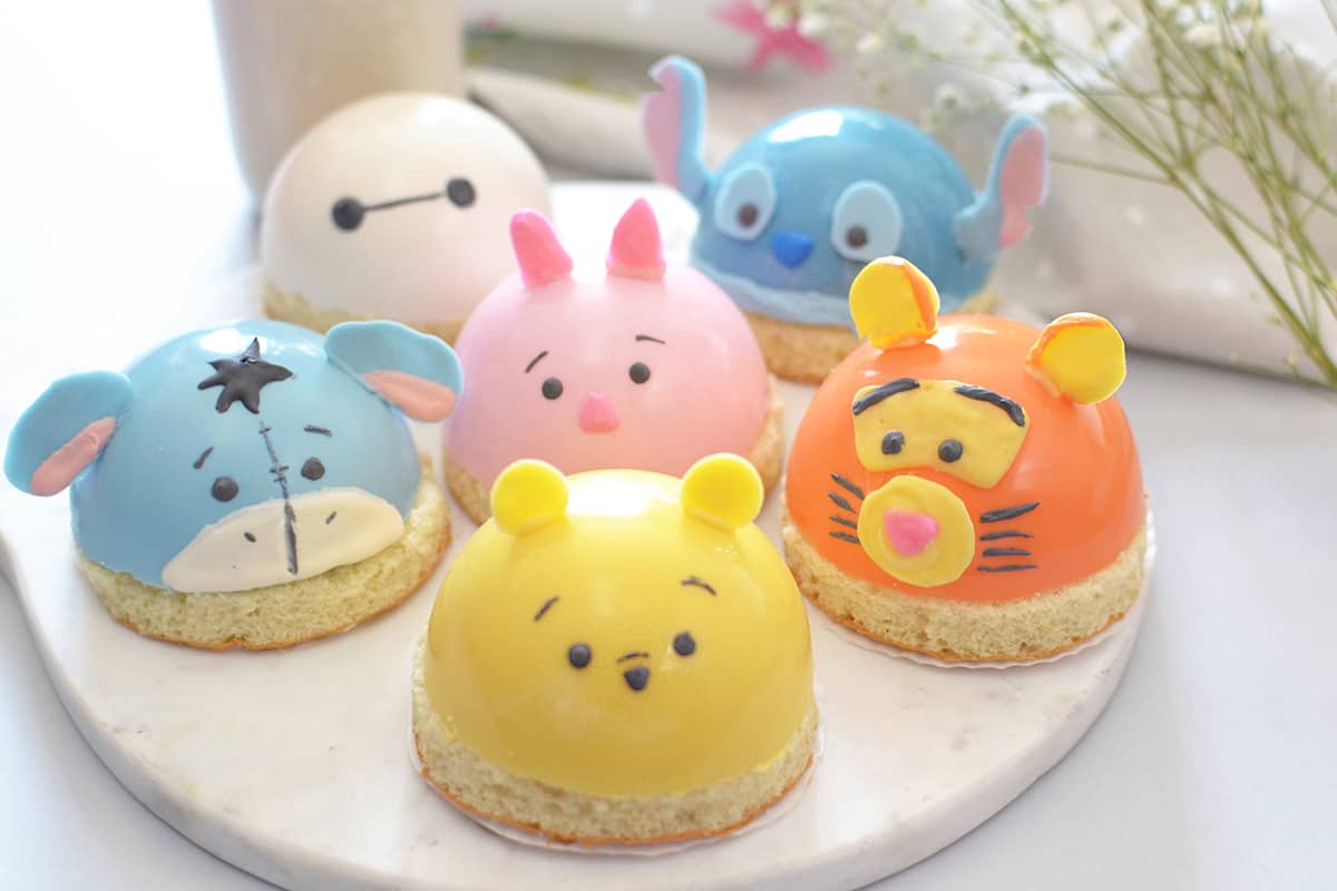 Six Disney character dome cakes line a marble platter, capturing theme park magic in every bite—perfect for any fan celebration.