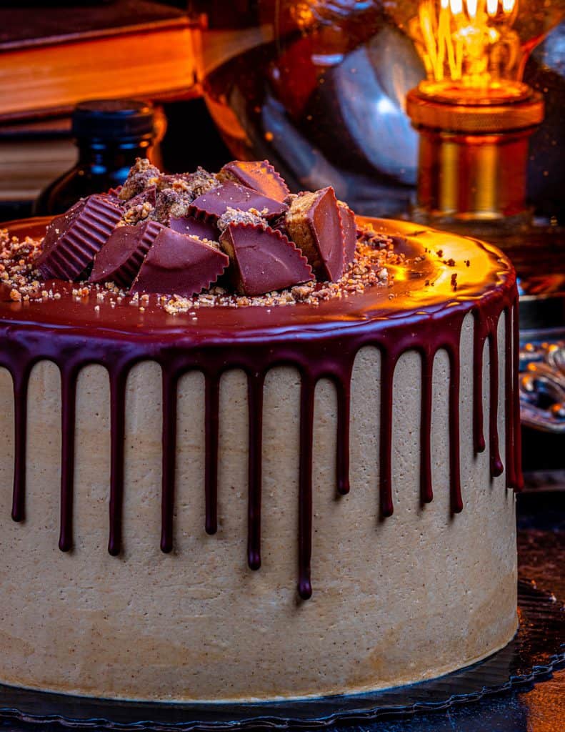 Gideon’s Bakehouse-inspired chocolate drip cake with peanut butter cups at Disney Springs, glowing in cozy, theme park lighting.