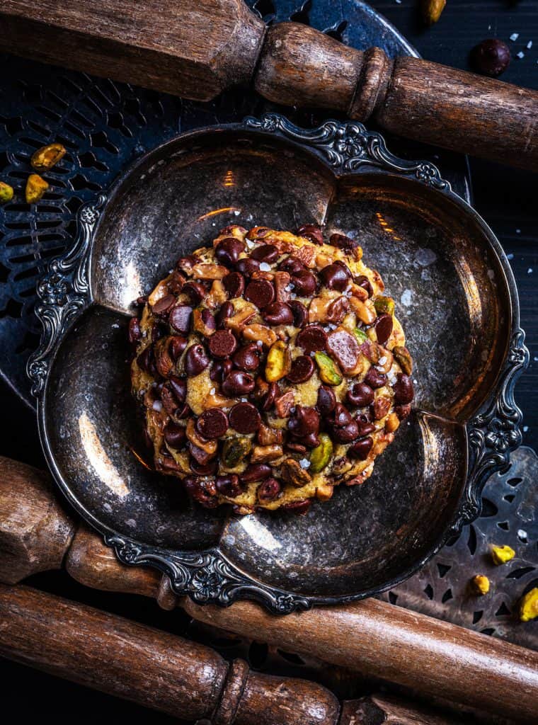 Gideon’s Bakehouse chocolate chip pistachio cookie on silver plate with rolling pins—Disney Springs’ sweet new treat!.