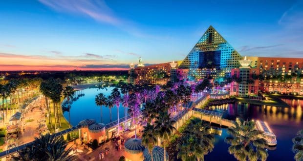 Vibrant sunset lights up the iconic Swan & Dolphin Resort and palm-lined lagoon at Walt Disney World Resort.