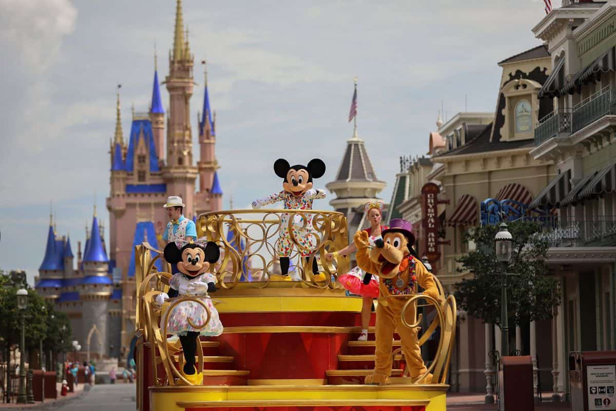 Mickey, Minnie, and Pluto wave from a colorful parade float with Cinderella Castle in the background at Walt Disney World.