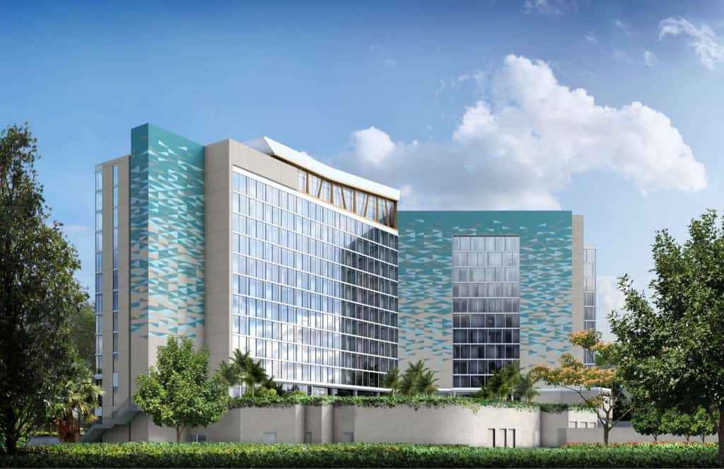 Sleek, Disney World-inspired resort building with teal details, towering glass windows, lush landscaping, and a bright blue sky.