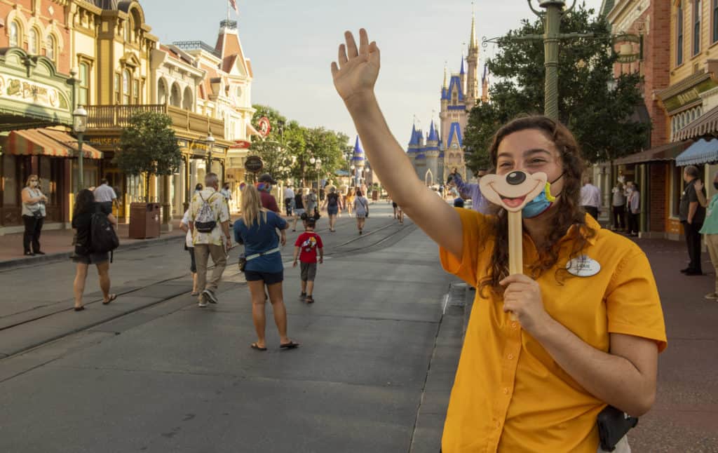 A cast member waving at guests behind a mask.