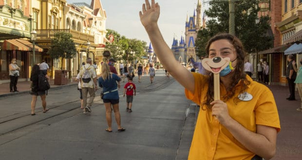 A cast member waving at guests behind a mask.