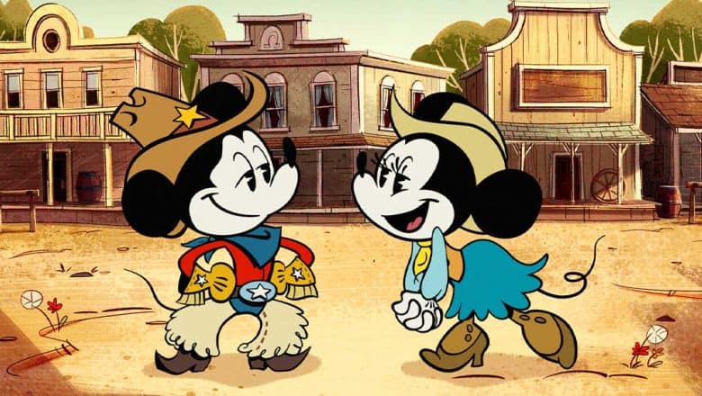 Mickey and Minnie Mouse, featured in The Wonderful World of Mickey Mouse on Disney+, wear cowboy outfits and share big smiles as they greet each other in a lively cartoon Wild West town, capturing the playful spirit fans love at Disney Parks.