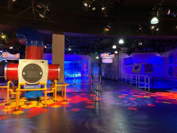 A vibrant, futuristic play zone filled with colorful pipes, glowing railings, and dynamic lighting effects on the walls and floor—capturing the whimsical atmosphere of EPCOT’s imaginative attractions at Walt Disney World.