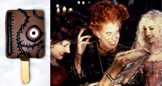 A whimsical chocolate ice cream bar shaped like a monster's face sits next to the Sanderson Sisters from Hocus Pocus as they eagerly pore over their spell book, capturing the playful magic of Disney’s Halloween celebration—an enchanting treat to enjoy while you pre-order our Spell Book Cake Pops!.