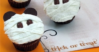 Indulge in our Mickey Mummy Cupcake—a Disney Parks favorite for Halloween! These chocolate cupcakes are transformed into adorable mummies with swirls of white frosting, chocolate Mickey ears, and candy eyes. Place them beside festive "trick or treat" signage for a magical touch at your Walt Disney World or Disneyland celebration. Perfect for adding spooky fun to your next park party or themed event!.