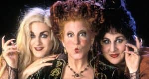 The Sanderson Sisters from Hocus Pocus come to life as three performers in elaborate witch costumes, complete with theatrical makeup and hair, strike a pose and engage guests with a direct gaze, capturing the movie's magical energy for fans at the park.