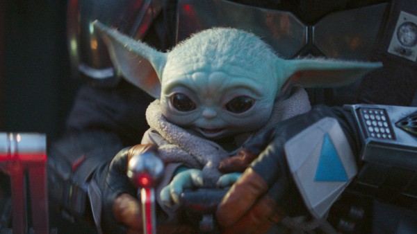 Grogu, the beloved green character with big ears and wide eyes from The Mandalorian, is cradled by Din Djarin in his unmistakable Mandalorian armor, bringing to life a fan-favorite moment from the hit Disney+ series recognized at Star Wars: Galaxy’s Edge.