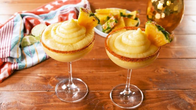 Frozen Dole Whip Margaritas with chili rims and pineapple wedges—sipping Disney magic at home, perfect for summer fans.