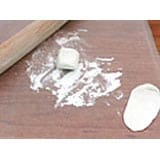 Baking props like a rolling pin, flour, and dough pieces on a rustic wooden counter evoke the backstage magic of creating spooky-themed cupcakes for your Halloween celebration at the park.