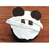 Panda-themed cupcake with white frosting and chocolate ears, styled like a playful park mascot treat, rests on a wooden table—an imaginative dessert that brings a whimsical twist to your theme park Halloween celebration, ideal for fans of fun and spooky snacks.