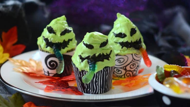 Halloween cupcakes designed like green monsters with gummy worm decorations, served on a white plate—imagine these festive treats featured at Universal Studios’ Halloween Horror Nights, adding a sweet touch to the spooky park festivities.