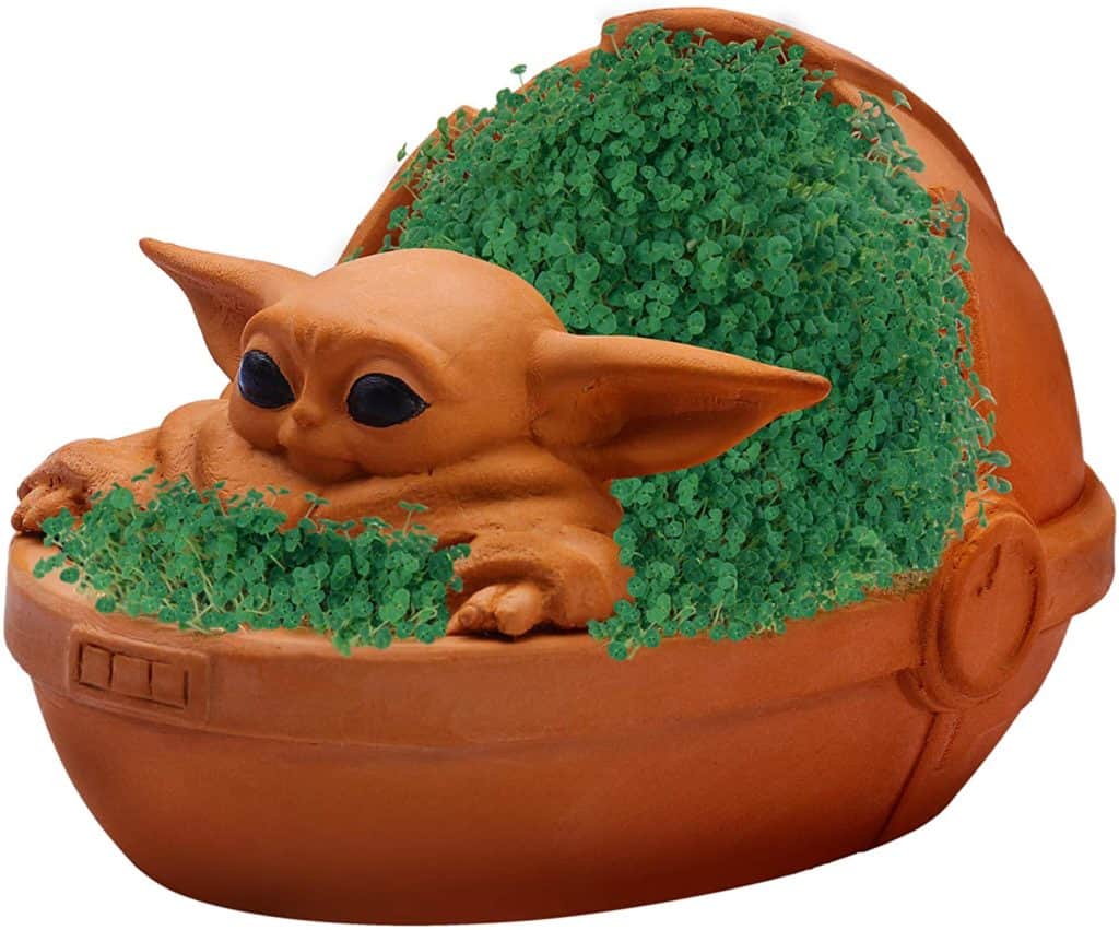 Baby Yoda-shaped terracotta planter styled like a Chia Pet, sprouting vibrant greenery—an out-of-this-galaxy collectible for Star Wars fans to showcase as part of their home or theme park-inspired decor.