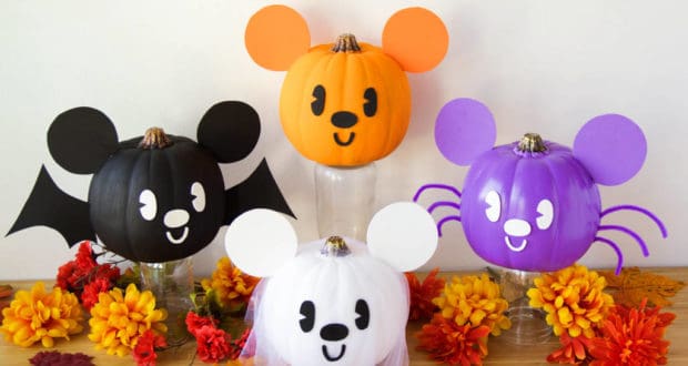 Four Disney character pumpkins with signature mouse ears, inspired by favorite park icons and painted for Halloween, are displayed as a festive centerpiece amid autumn leaves and flowers, bringing magical Disney Parks decor to your celebration.