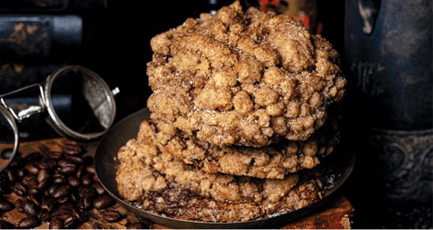 A tempting stack of four crumbly Coffee Cake Cookies on a metal plate, surrounded by scattered coffee beans—this beloved Disney Springs treat is a must-try from Gideon’s Bakehouse for theme park foodies.