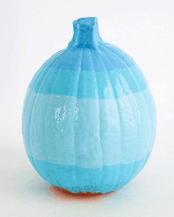 A pumpkin decorated with playful horizontal blue stripes on white, evoking the whimsical magic of Winnie the Pooh’s Hunny Pot as seen in Disney park seasonal displays.