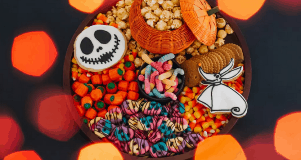 A Halloween snack platter inspired by The Nightmare Before Christmas, piled high with popcorn, candy corn, gummy worms, classic cookies, and Jack Skellington-themed treats—perfect for enjoying during a night of spooky fun at your favorite theme park.