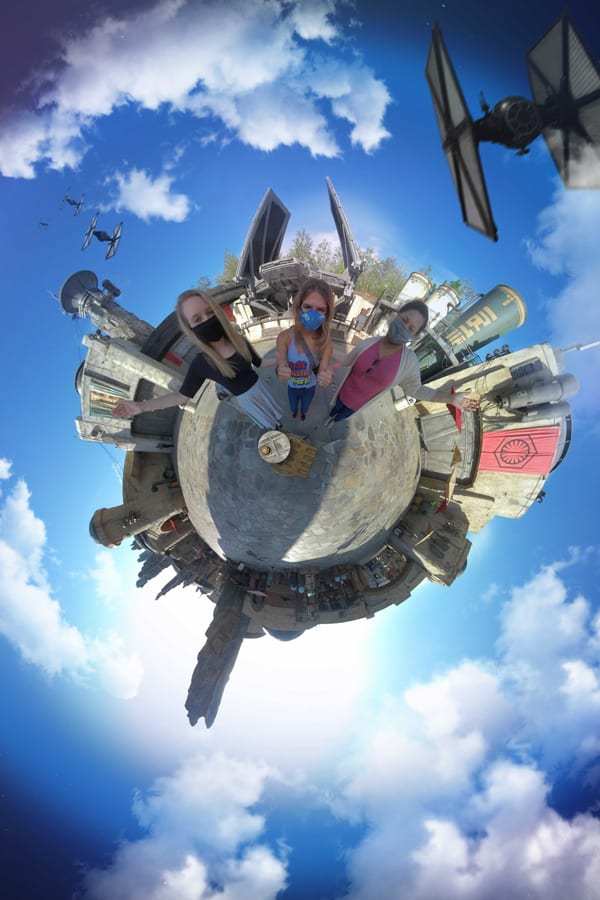 Guests strike a pose in Star Wars: Galaxy’s Edge at Disneyland, surrounded by TIE fighters and immersive Batuu architecture beneath a brilliant blue sky—a must-capture Disney PhotoPass moment.