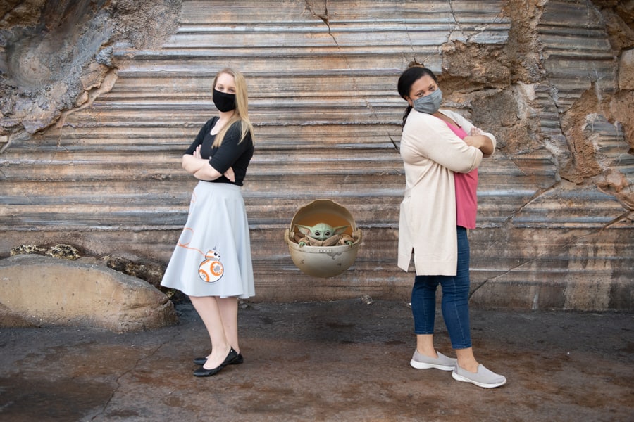 Guests in themed face masks strike a playful back-to-back pose with Grogu between them, all set against Batuu’s rugged landscape—an unforgettable Star Wars moment for your Disney PhotoPass Memory Maker.